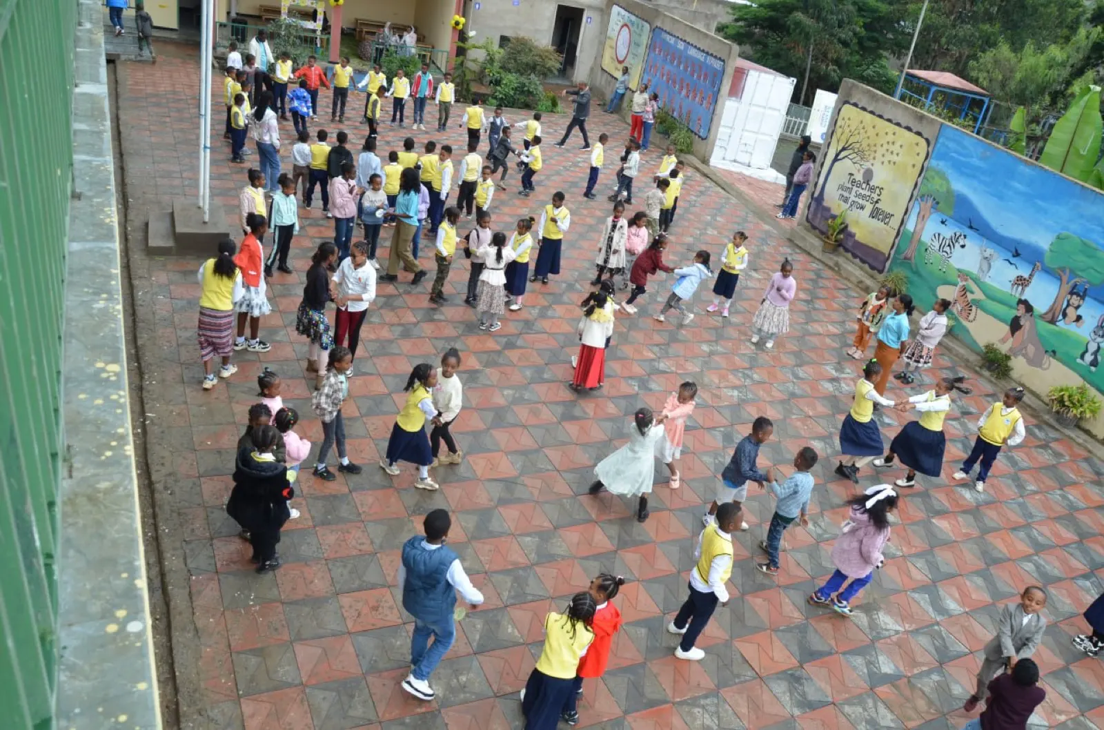 Keti students and staff dance together in the school courtyard.