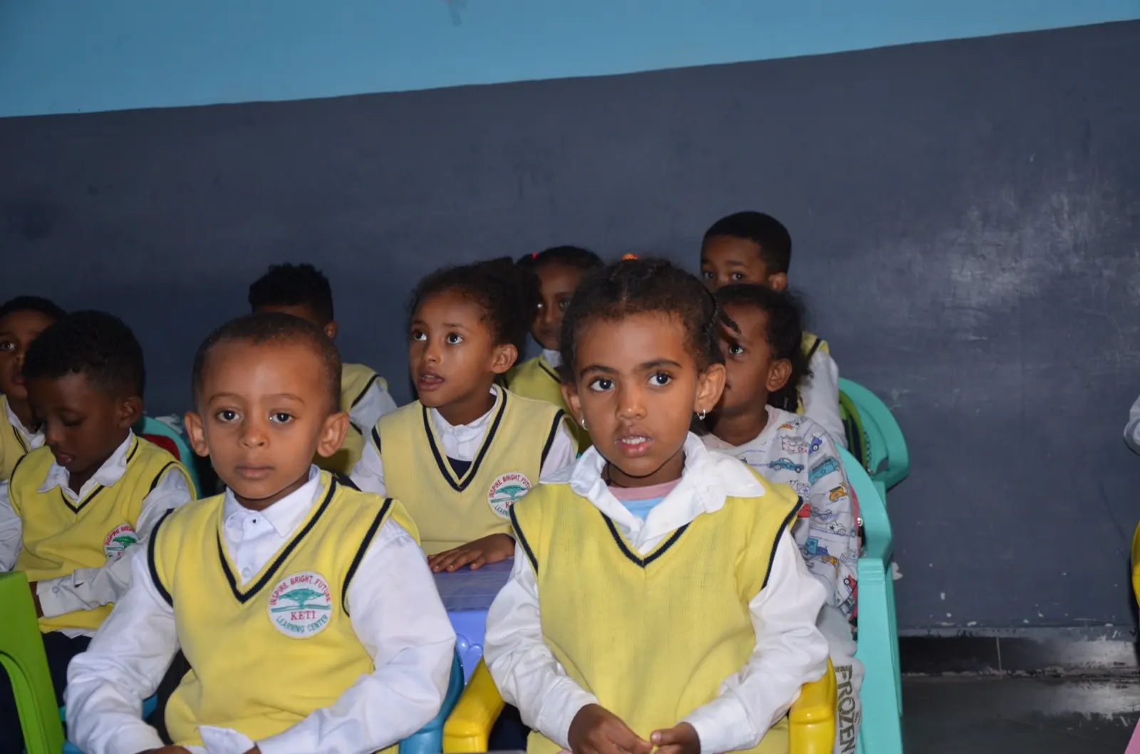 Kindergarten children seated at tables in a Keti classroom.