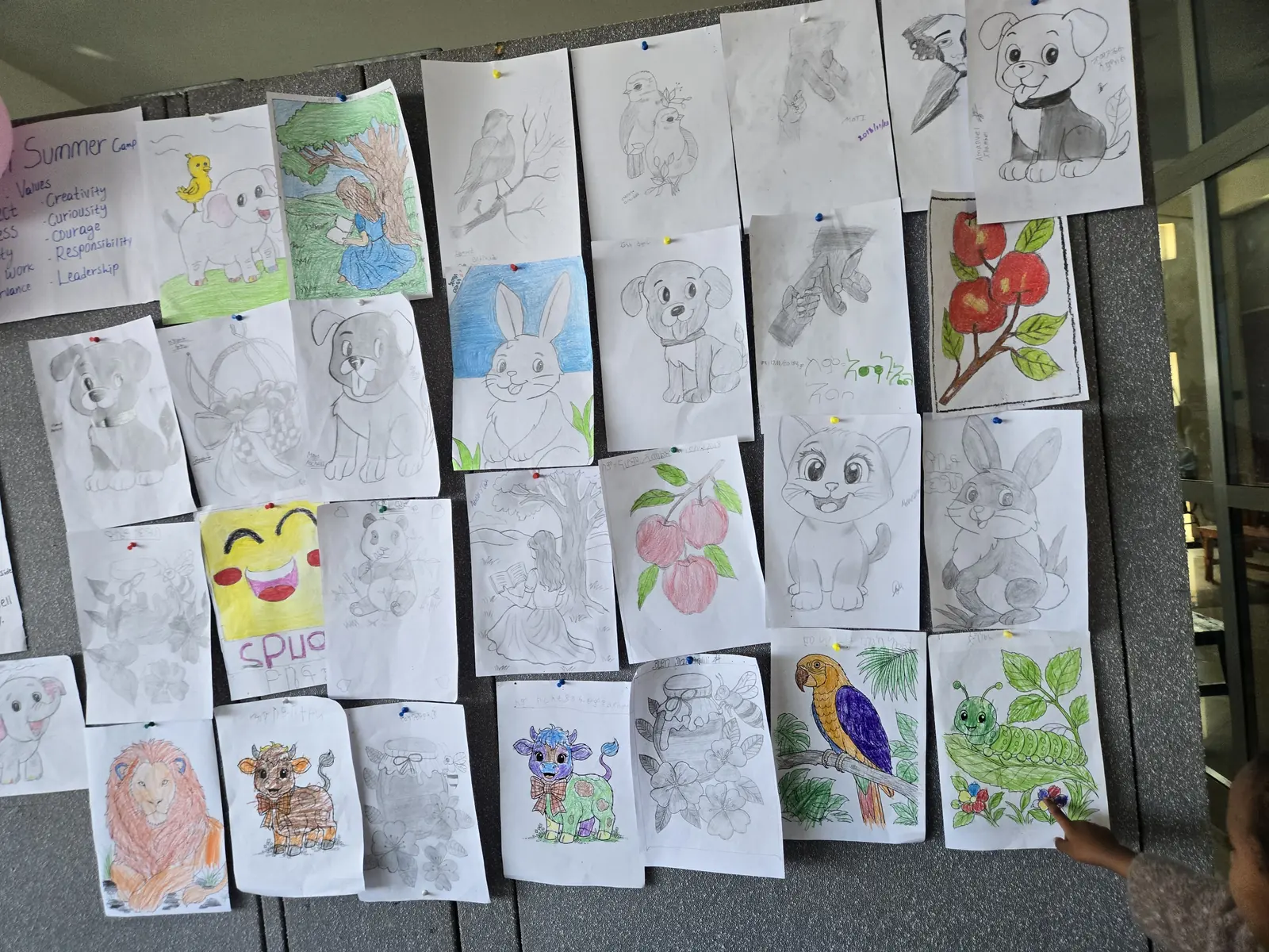 A wall of children’s drawings and paintings from camp.