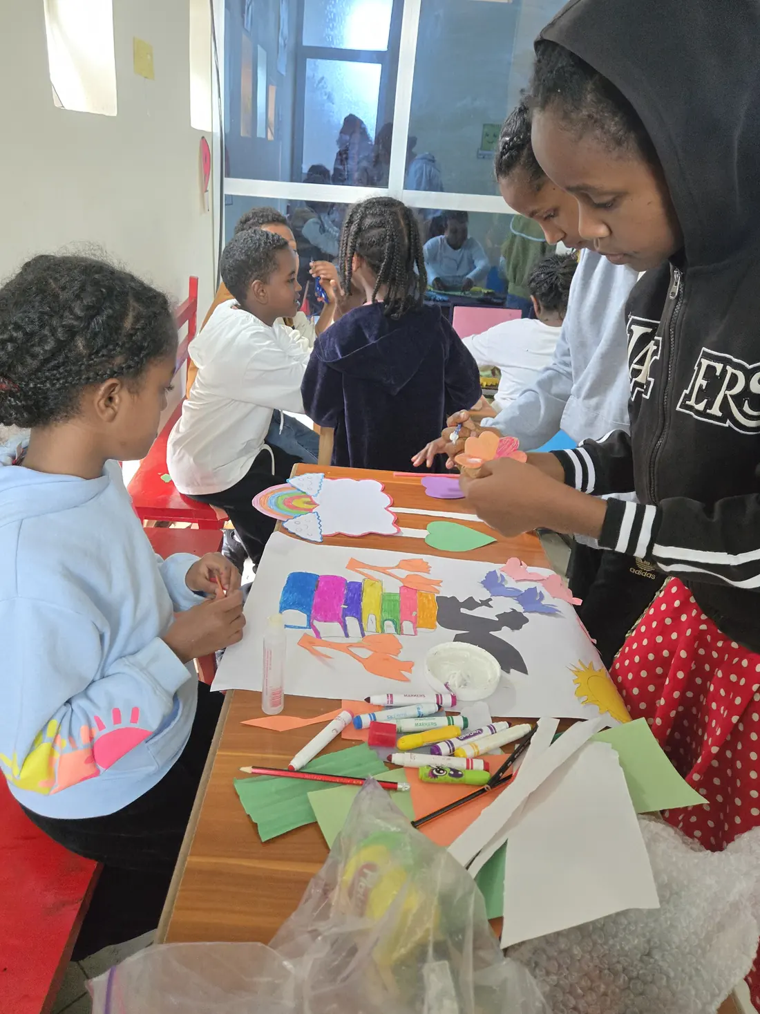 Children cut out and colour paper shapes.