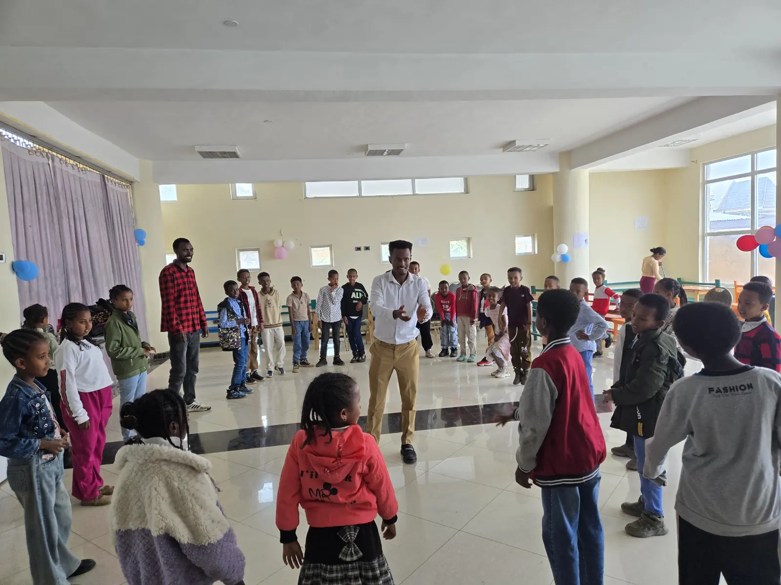 Children play a circle game in the library hall.