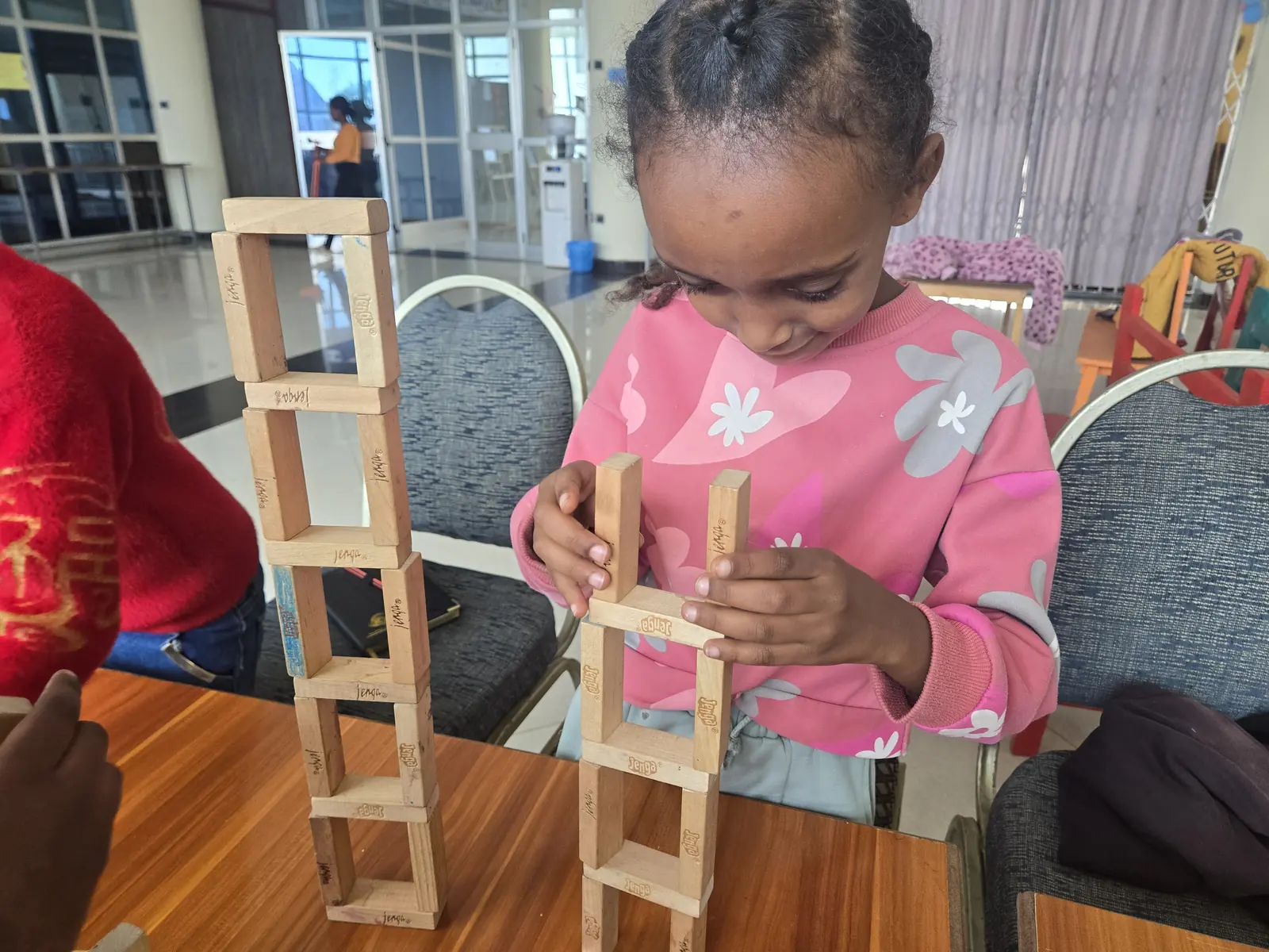 A girl smiles as she builds a wooden block tower.