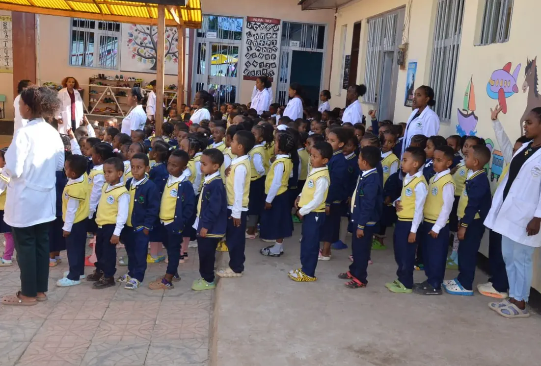 Kindergarten children line up in the courtyard with their teachers.