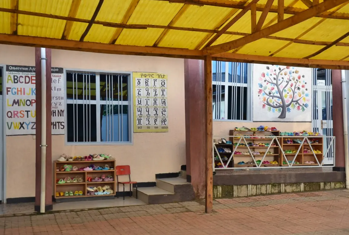 The covered KG porch with alphabet charts, toy shelves and a painted tree.