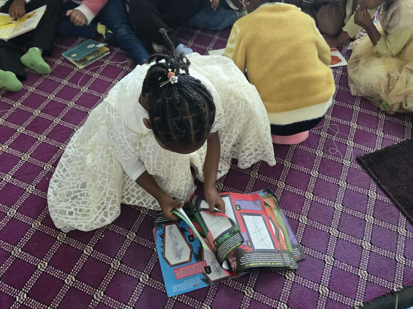 A girl kneels to choose from a pile of picture books.