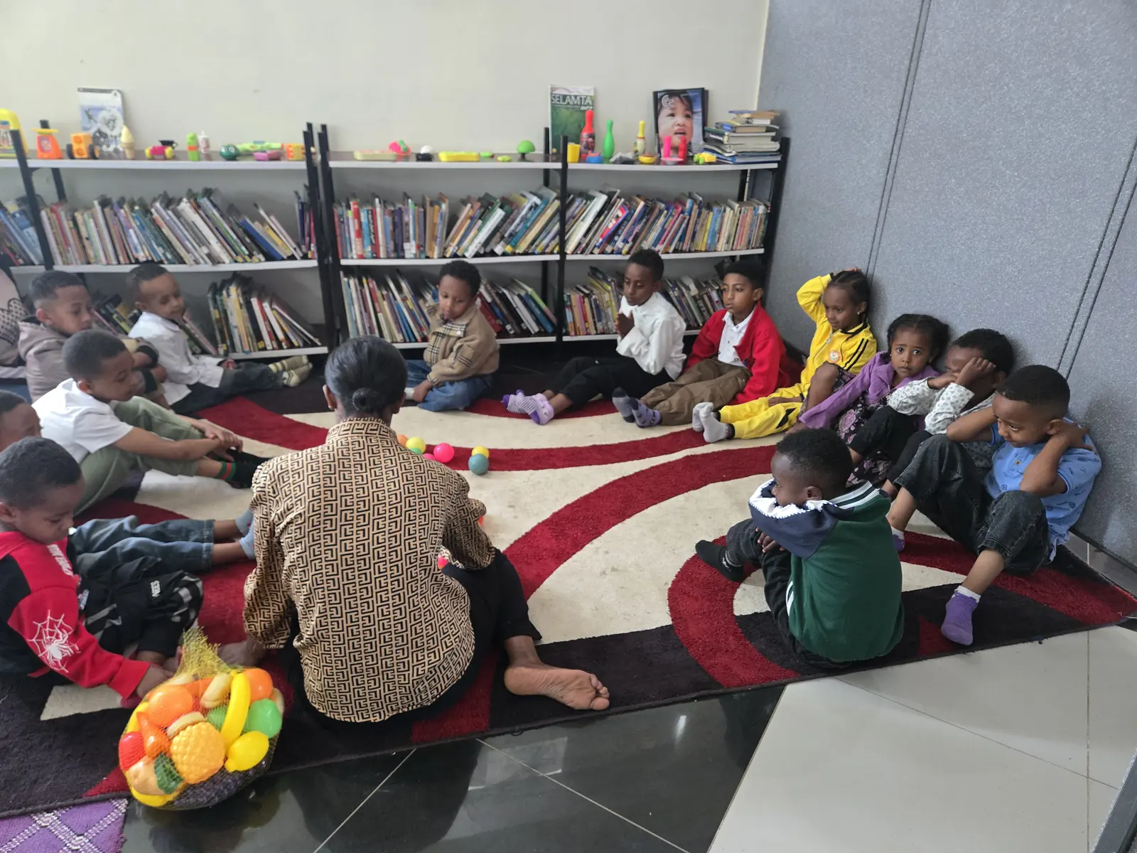 A reader leads a story circle with young children on the library rug.