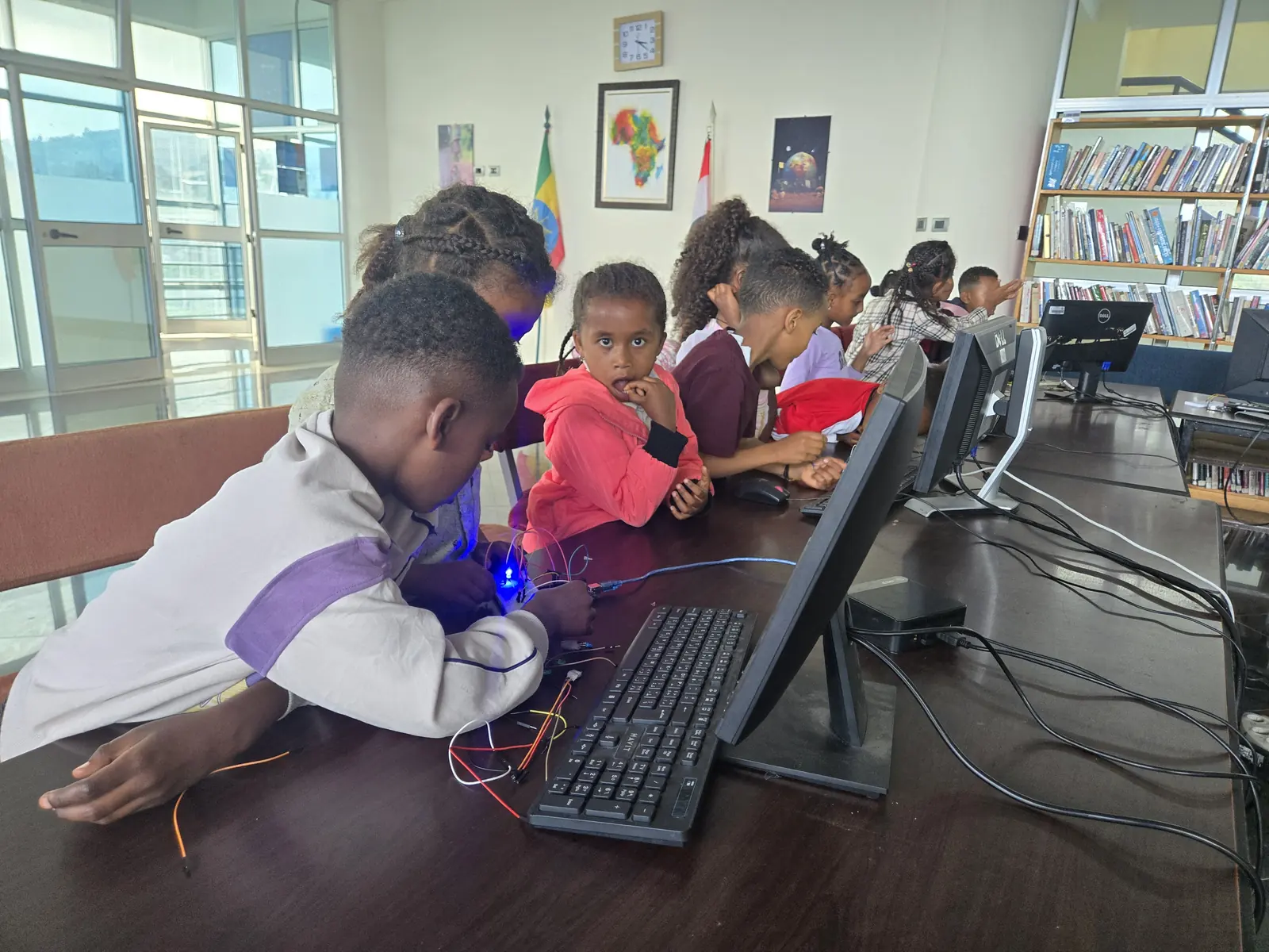 Children work at a computer connected to an electronics kit in the library.